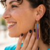 orecchini pendenti di perline colorate in vetro indossate da donna con capelli scuri e outfit turchese