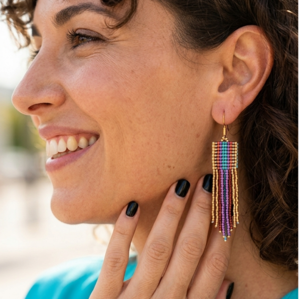 orecchini pendenti di perline colorate in vetro indossate da donna con capelli scuri e outfit turchese