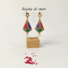 Orecchini pendenti forma a lanterna tridimensionale piena colore oro, nero, blu, verde e rosso su uno sfondo chiaro con perline in vetro rosse