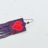 Dettaglio Orecchini di perline viola iridescenti a frangia con cuore rosso