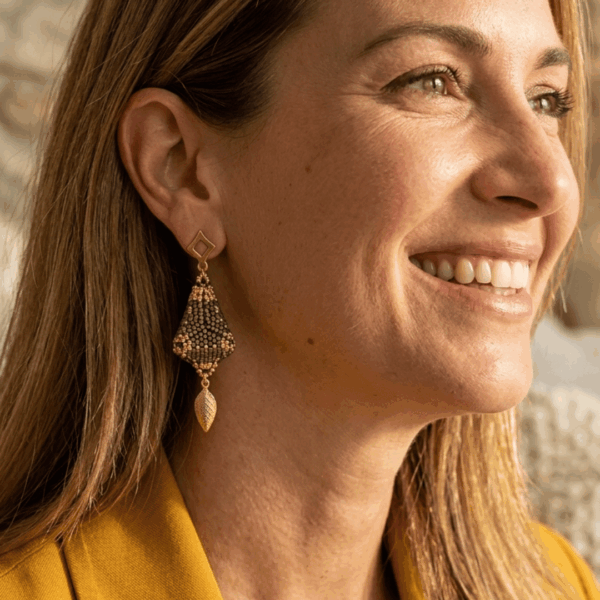 Orecchini marroni chandelier di perline tridimensionali indossati da donna con i capelli lunghii biondi e outfit senape