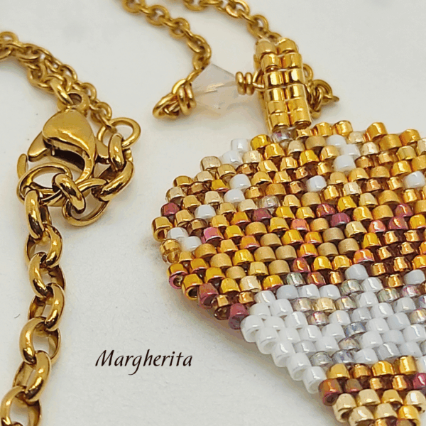 Dettaglio collana a forma di mongolfiera "Margherita" firmata Vanitage Gioielli, realizzata a mano con perline di vetro sfumate oro, bianco e bronzo, dorata di catena dotata in acciaio e ciondolo a stella in argento 925 su sfondo chiaro
