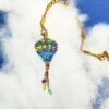 Collana ciondondolo Mongolfiera blu, realizzata a mano con perline in vetro sullo sfondo un cielo nuvoloso