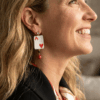orecchini pendenti di perline design asso di cuori con cristalli indossato da donna bionda con giacca nera e foulard fantasia
