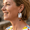 orecchini pendenti di perline design asso di fiori con cristalli indossato da donna bionda con outfit colorato