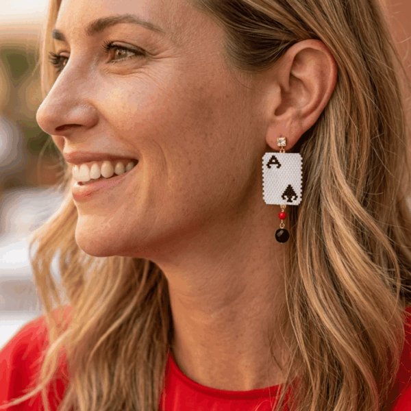 orecchini pendenti di perline design asso di picche con cristalli indossato da donna bionda con outfit rosso