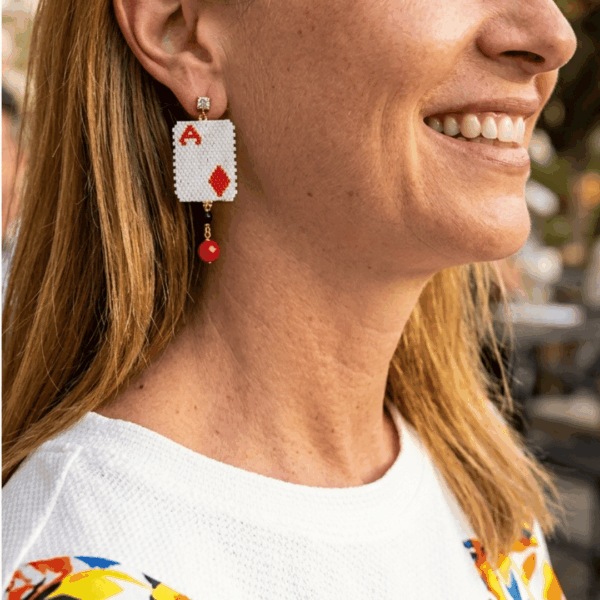 orecchini pendenti di perline design asso di quadri con cristalli indossato da donna bionda con outfit colorato
