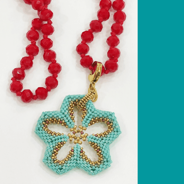 Collana Fiore turchese realizzato a mano con perline in vetro e collana, con cristalli rossi a nodi. Sfondo bianco.