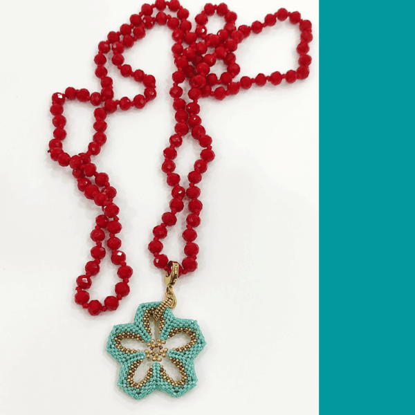 Collana Fiore turchese realizzato a mano con perline in vetro e collana, con cristalli rossi a nodi. Sfondo bianco.