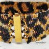 Inquadratura ravvicinata di un bracciale artigianale a fascia larga con motivo maculato leopardato, realizzato con perline Miyuki nere, oro e bronzo metallizzato. Al centro spicca la chiusura a baionetta in metallo dorato lucido.