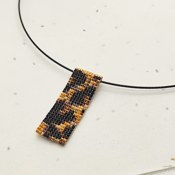 Dettaglio di collana corta girocollo in stile animalier ghepardato, su sfondo chiaro