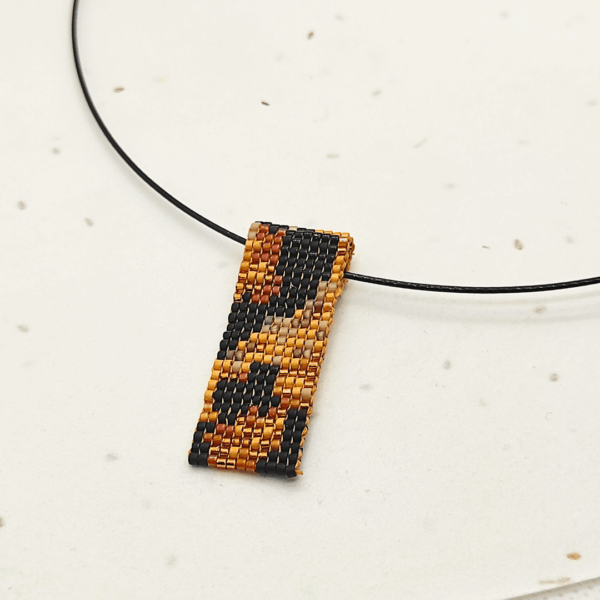 Dettaglio di collana corta girocollo in stile animalier leopardato, su sfondo chiaro