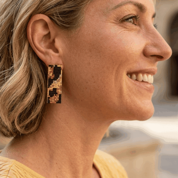 Orecchini a lobo in stile animalier leopardato indossato da donna con i capelli biondi e outfit beige