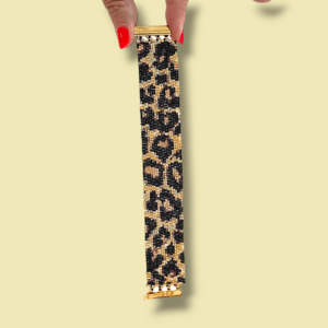 due dita con smalto rosso tengono un bracciale a fascia di perline in vetro design animalier