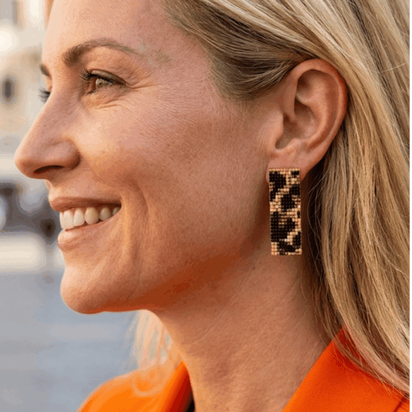 Orecchini a lobo in stile animalier ghepardato indossato da donna con i capelli biondi e outfit arancione