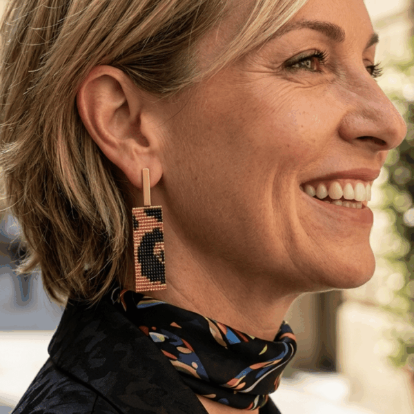 Orecchini pendenti in stile animalier indossato da donna con i capelli biondi e outfit nero