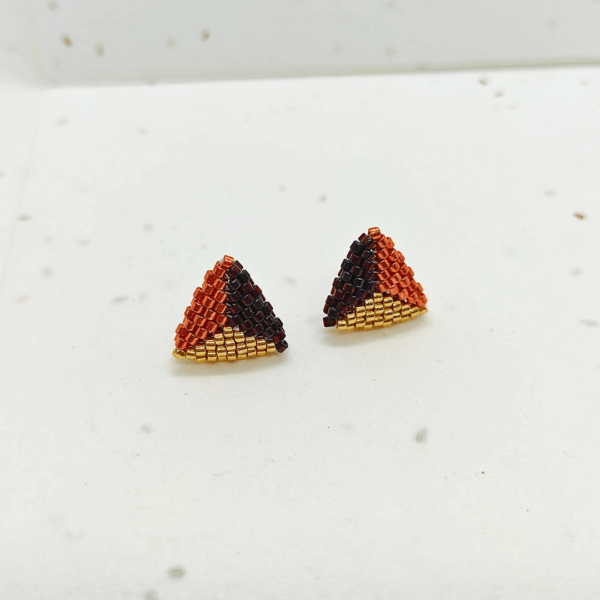 orecchini a lobo a triangolo dorati e colorati su sfondo chiaro