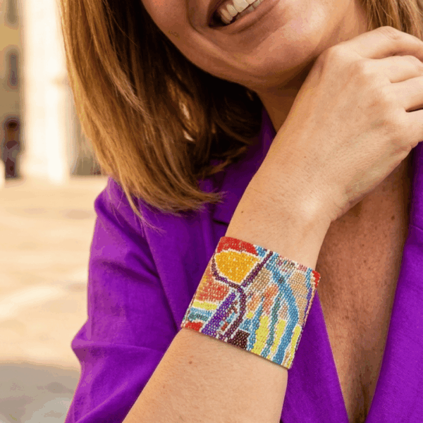 Bracciale a fascia alta di perline colorate design astratto con chiusura scorrevole in acciaio, indossato da donna con outfit viola