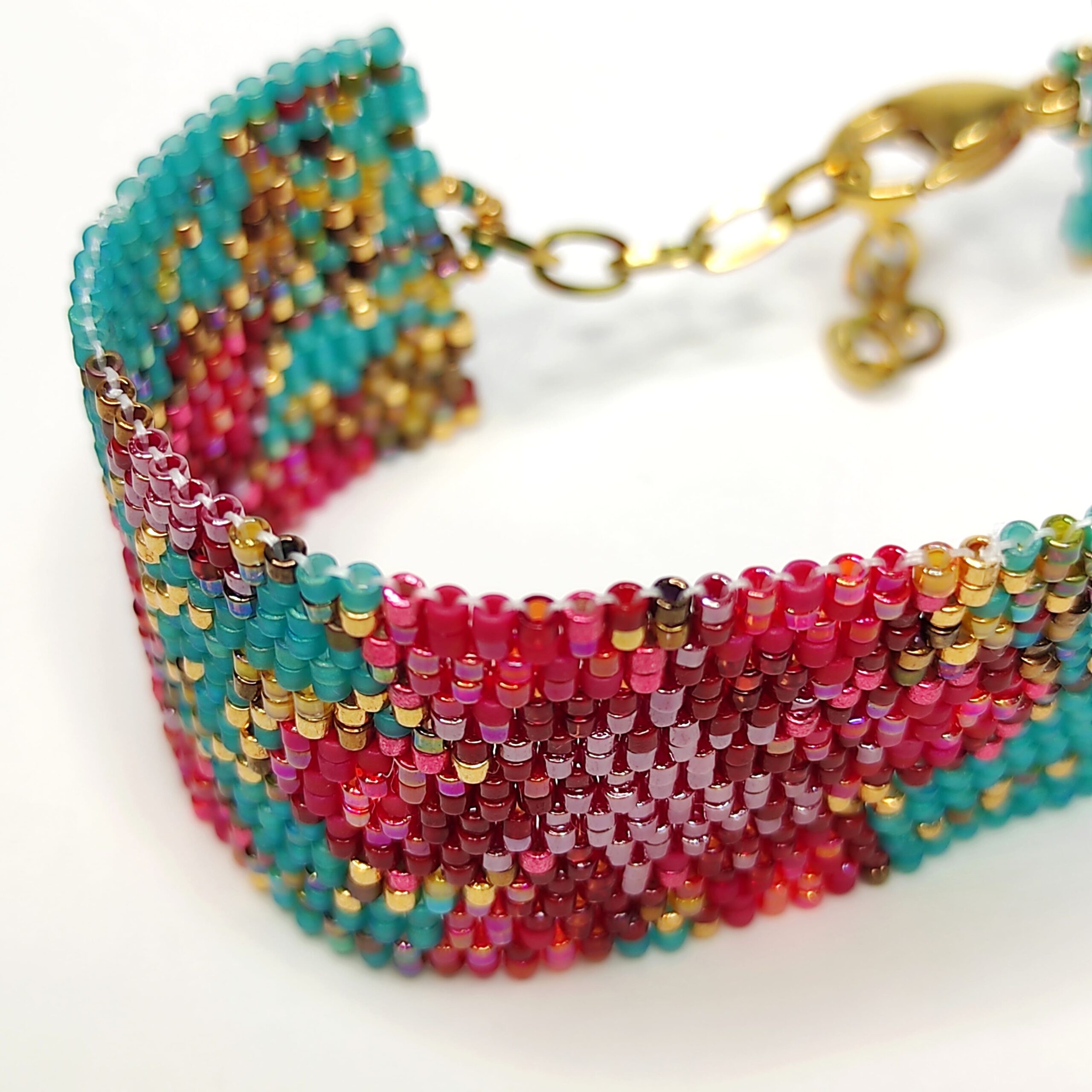 Bracciale di perline design floreale rosso si sfondo turchese con chiusra in acciaio dorata.