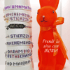 Bracciali con parole di perline in vetro e catena in acciaio con charm cuore in argento 925 su sfondo chiaro, acconto un coniglio arancione