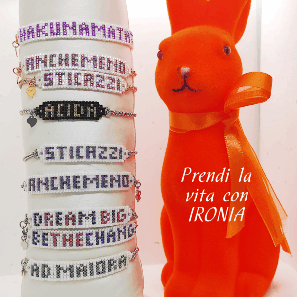 Bracciali con parole di perline in vetro e catena in acciaio con charm cuore in argento 925 su sfondo chiaro, acconto un coniglio arancione