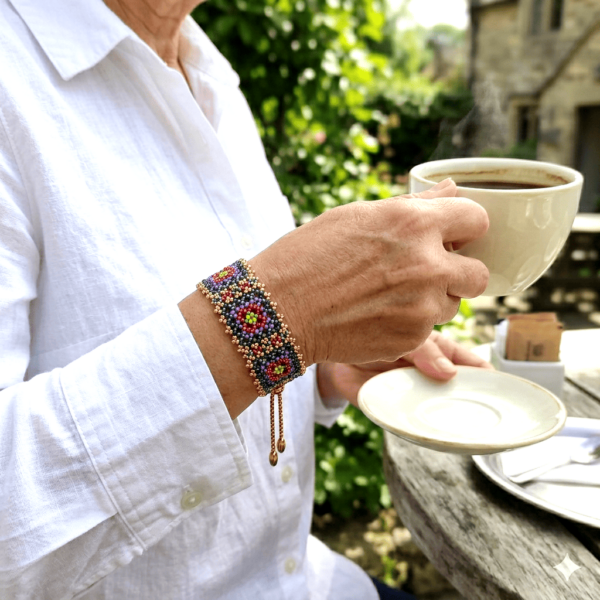Modella che indossa il bracciale granny modello Soul di perline, con una camicia bianca, mentre beve un caffè
