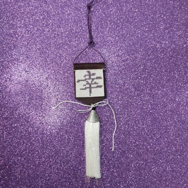 Amuleto Kanji della felicità, realizzato con perline in vetro e nappa bianca pendente, su sfondo viola