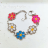 Bracciali margherite di perline fatte a mano con catena in acciaio su sfondo di carta bianca.