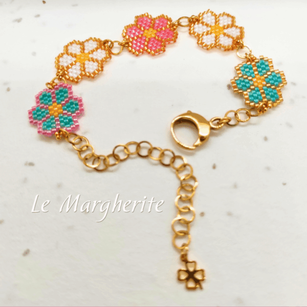 Bracciali margherite di perline fatte a mano con catena in acciaio dorato su sfondo di carta bianca