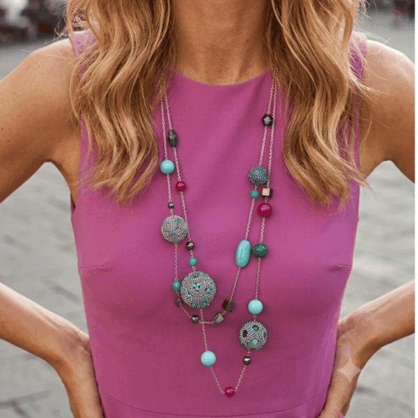 Collana lunga multifilo con sfere di perline e cristalli, pietre dure, alta bigiotteria indossata da donna con maglia color malva