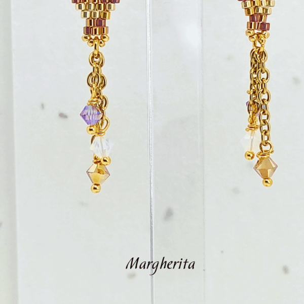 Dettaglio orecchini pendenti a forma di mongolfiera modello Margherita di Vanitage Gioielli, fatti a mano con perline di vetro oro, bronzo e bianche, completati da cristalli luminosi.