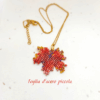 Collana con ciondolo a forma di piccola foglia d'acero rossa e arancione, realizzata con un mosaico di perline di vetro tessuto a mano e abbinata a una catenina dorata.