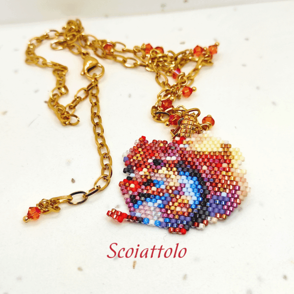 Collana fatta a mano con ciondolo a forma di scoiattolo colorato, realizzata con un mosaico di perline di vetro e abbinata a una catenina dorata con piccoli cristalli arancioni.