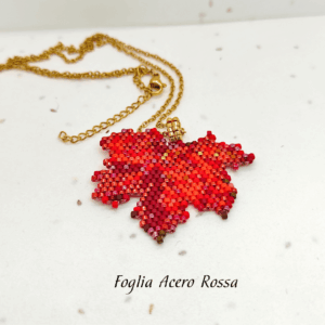 Collana fatta a mano con ciondolo a forma di foglia d'acero rossa e bordeaux, creata con un mosaico di perline di vetro e abbinata a una catenina dorata.