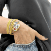 Bracciale con teschio messicano in perline colorate intrecciato su cordino blu in macramè, indossato al polso insieme a bracciali multifilo.