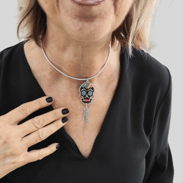Collana Vanitage con pendente teschio messicano in perline colorate e frange pendenti di catenelle argentate, indossata su cordino rigido argento.