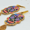 Dettaglio Orecchini pendenti Vanitage con teschio messicano in micro-perline multicolor e lunghe frange di catenelle argentate a movimento fluido, indossati al lobo.